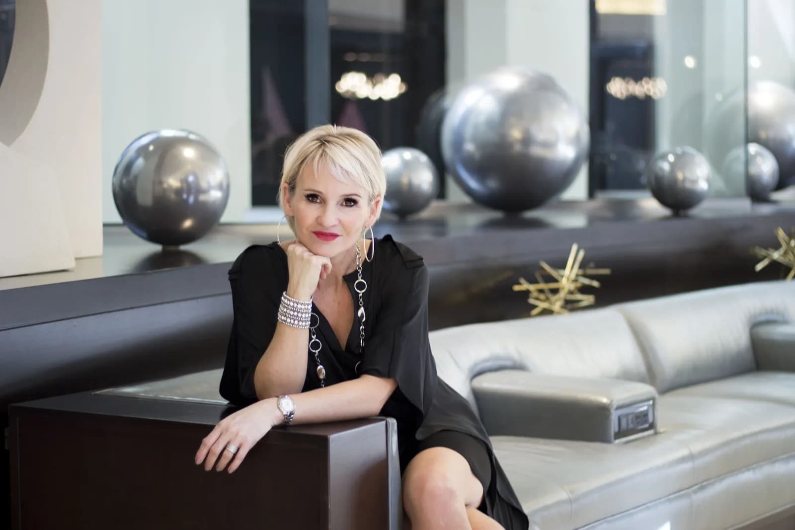 Linda in a black outfit seated in a modern lounge