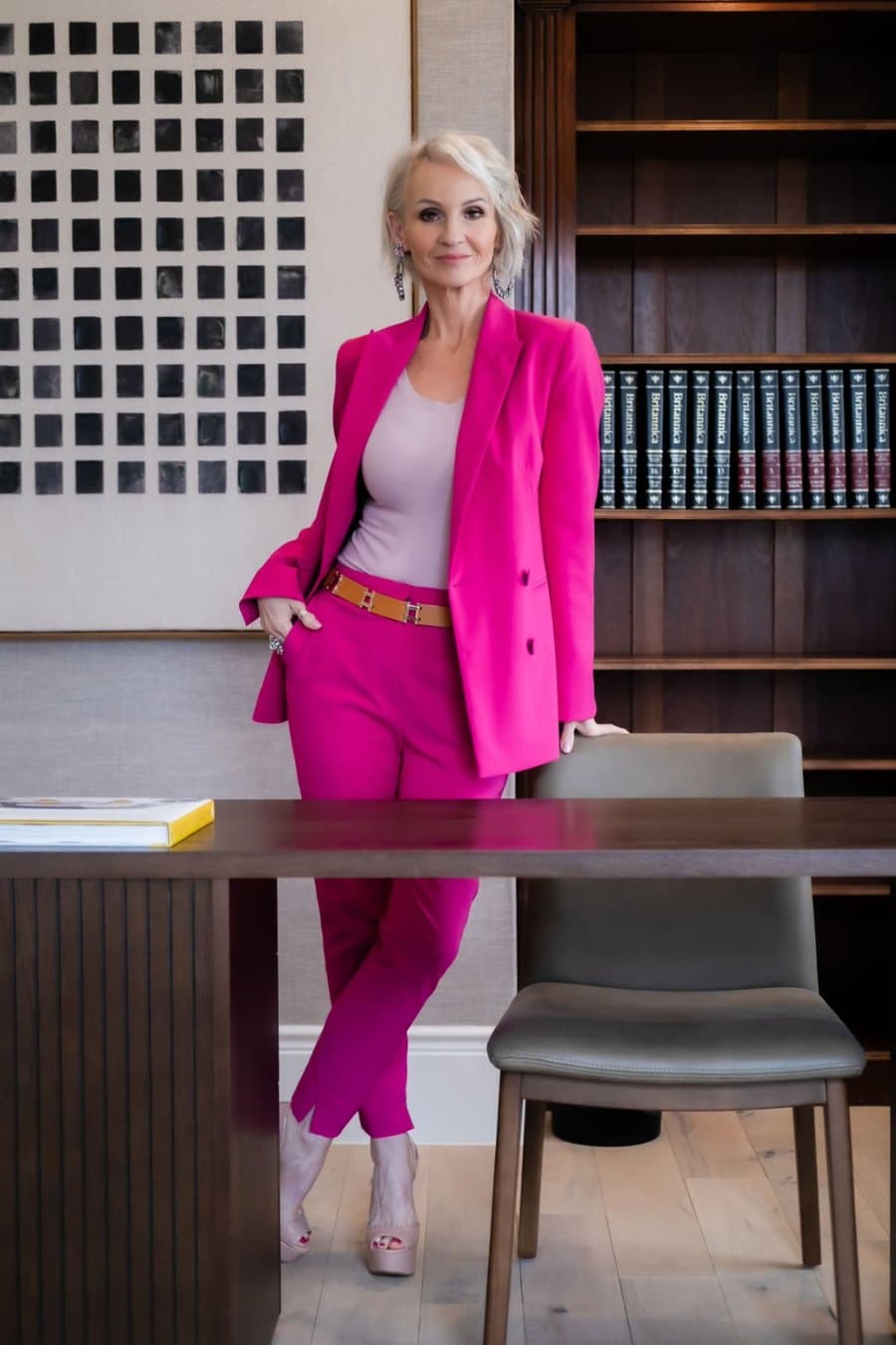 Linda Paige in a hot pink power suit standing in a library, executive coach teaching the 4-Pillar Confidence Framework