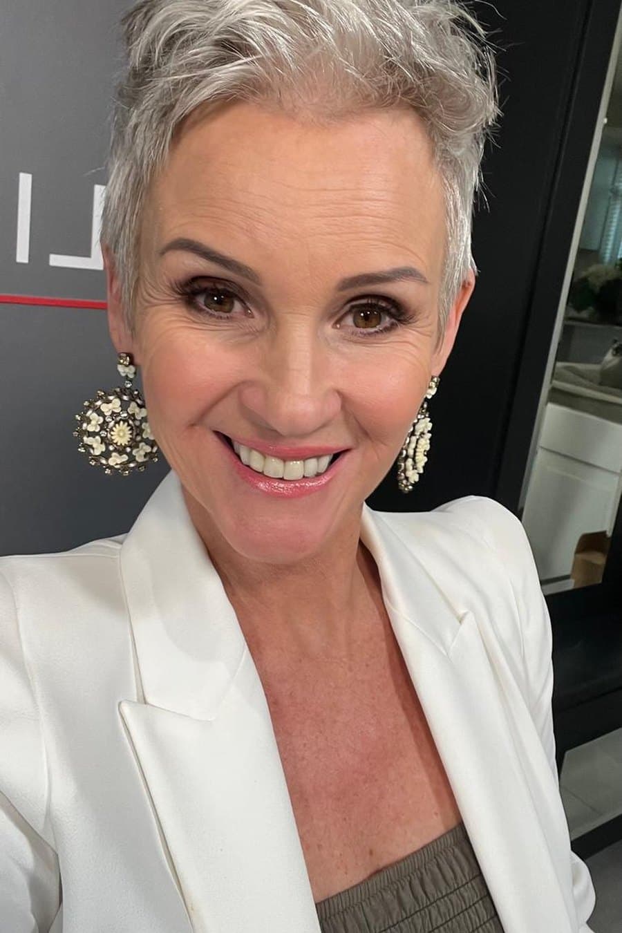 Linda Paige in a blue silk blouse, smiling with hand on chin, ready for a strategy call