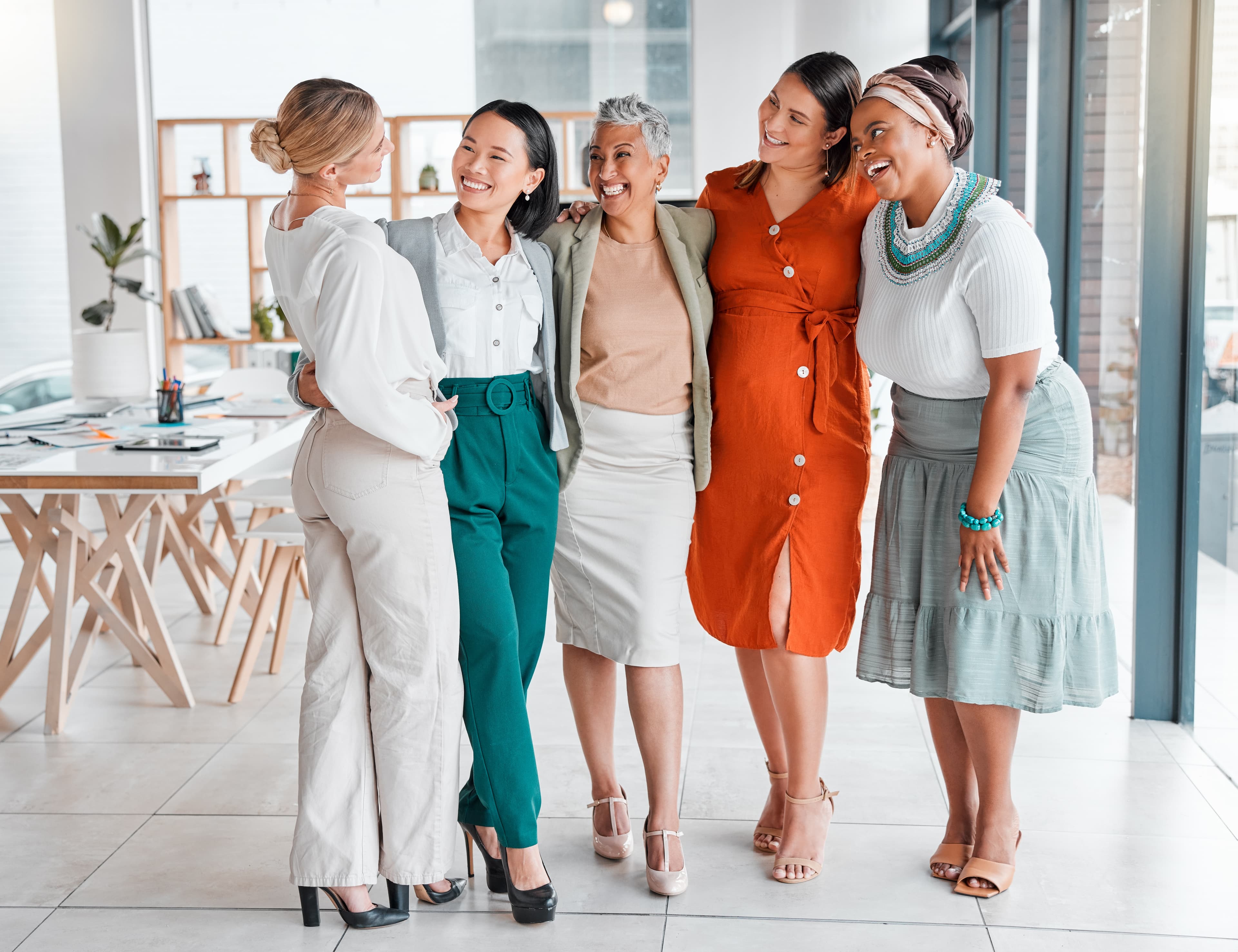 Group of confident women standing together in stylish professional outfits, smiling and connecting in a modern workspace — Dress To Connect flagship programme