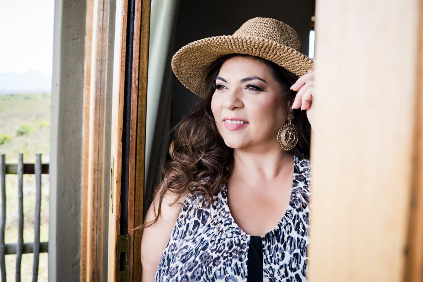 Minita in a straw hat and leopard print top at an open door